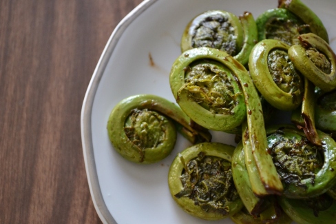 Pan fried fiddleheads with balsamic vinegar on a white plate